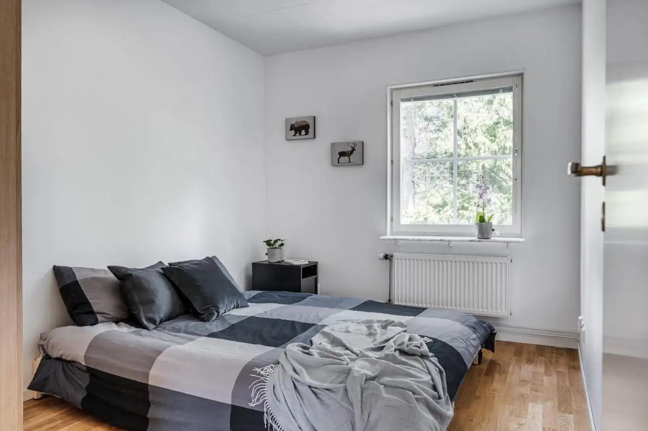 Minimalist bedroom with grey checkered bedding in Uppsala rental