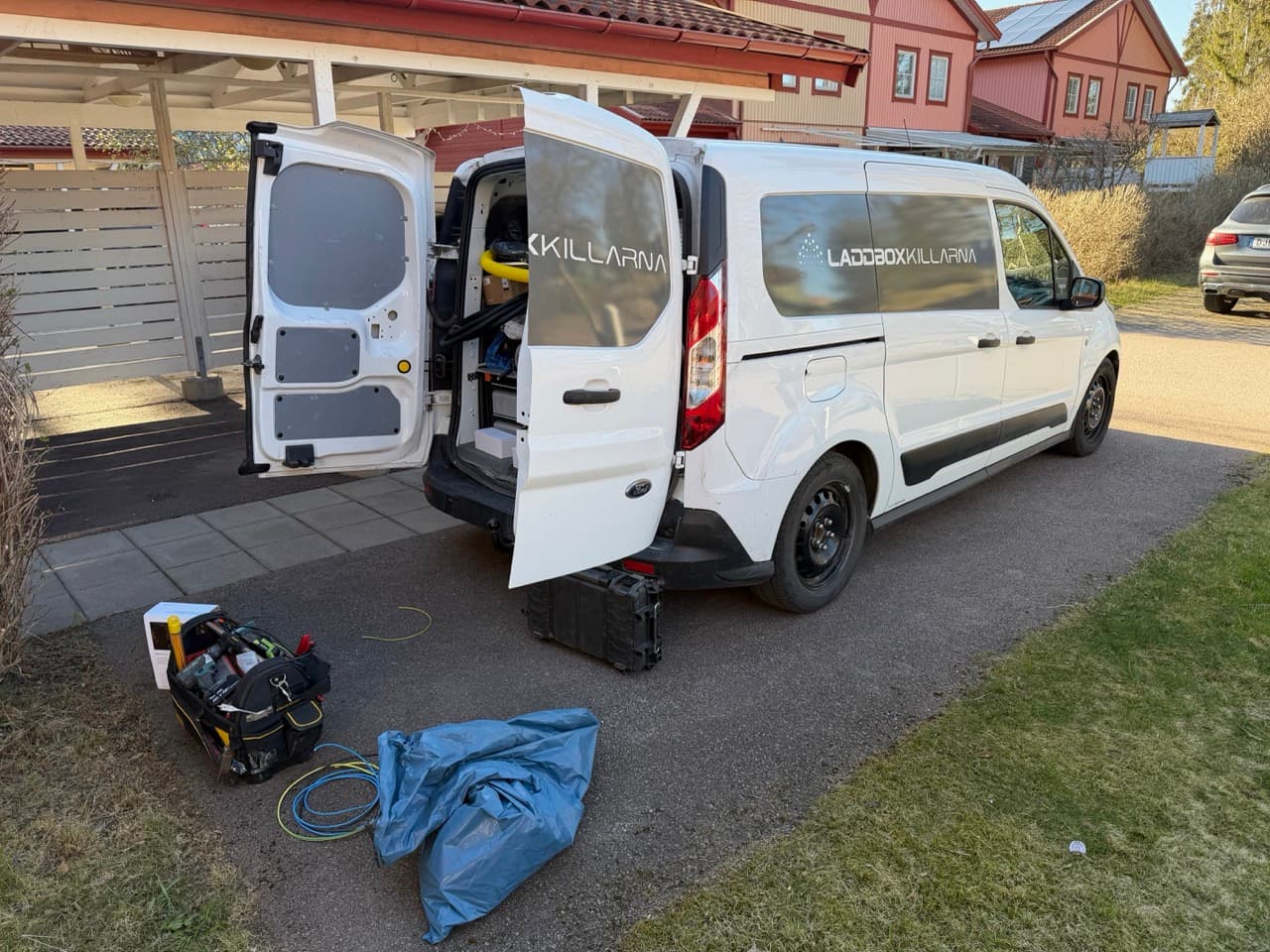 Laddboxkillarna van with rear doors open and tools laid out for an EV charger install in Uppsala, Sweden