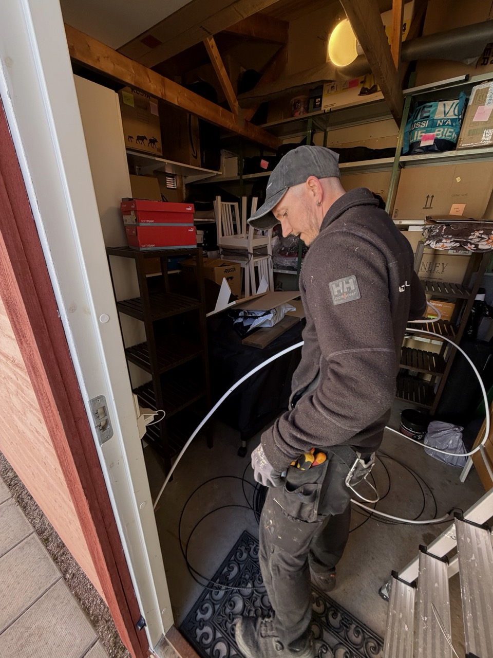 Magnus inside the storage room pulling cable through the conduit