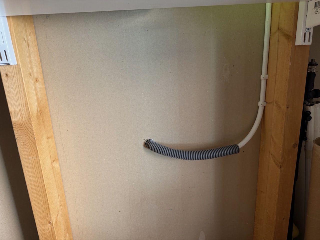 Storage room wall showing the flexible conduit and new white cable running up