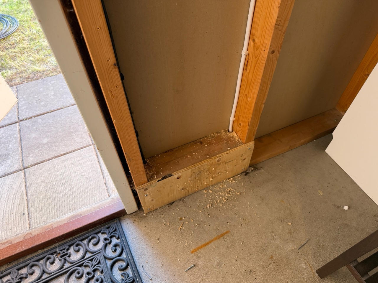 Storage room near doorway with wooden cover removed, sawdust on floor exposing conduit