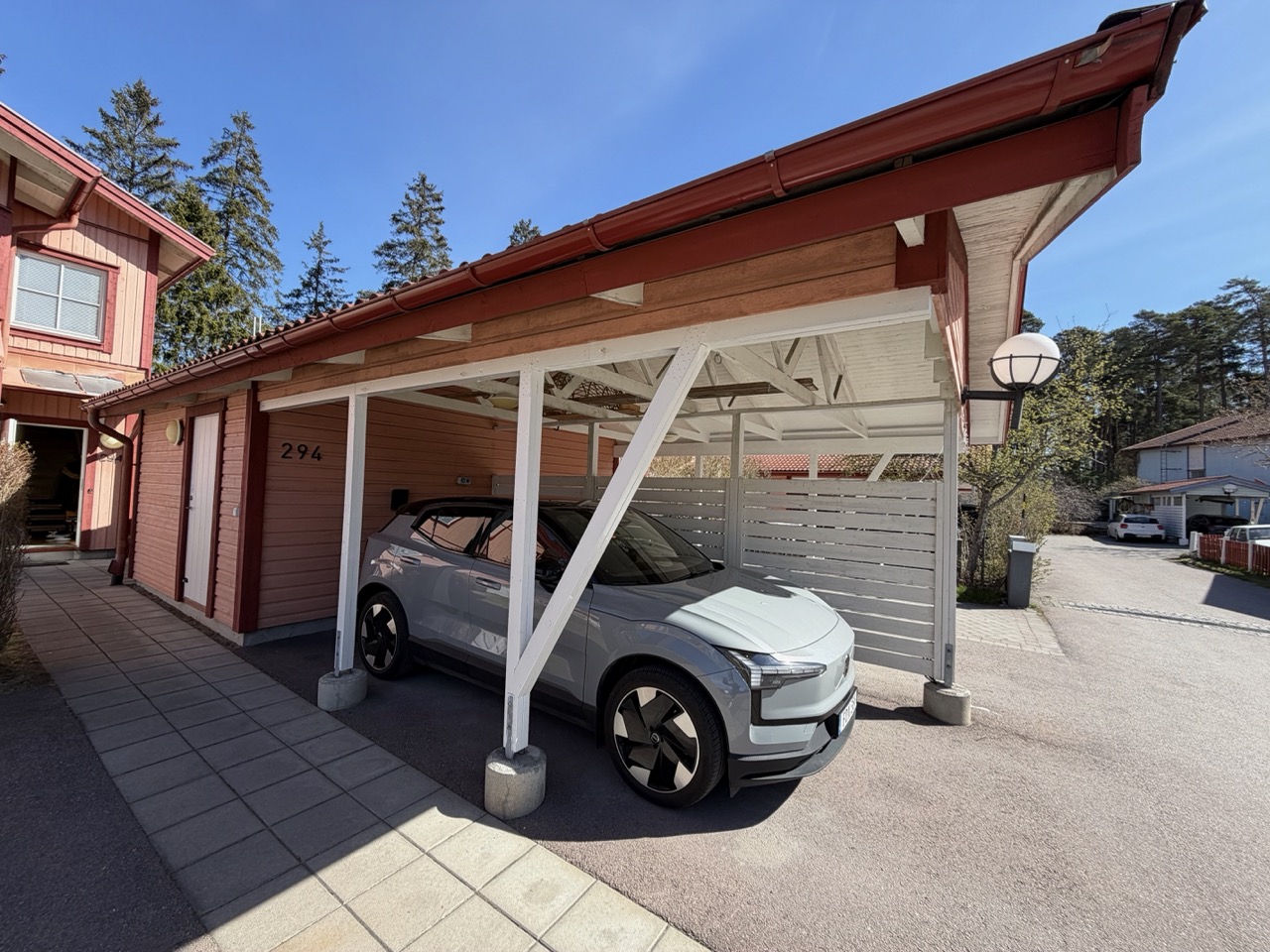 Volvo EX30 parked under the carport, Zaptec Go 2 visible on the wall behind